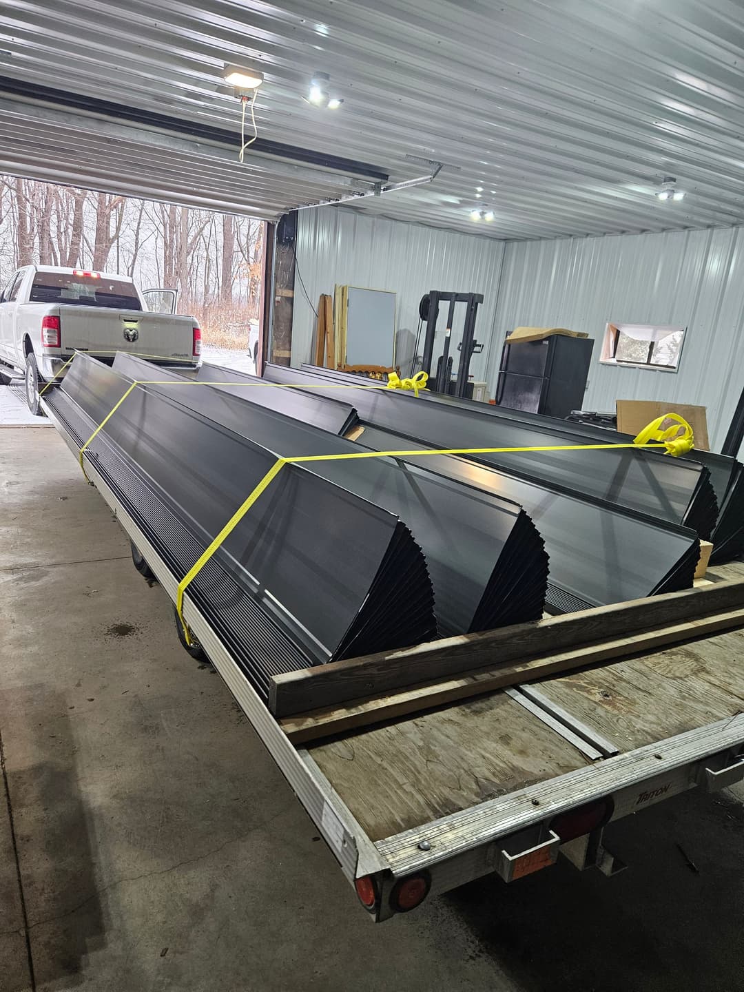 Metal roofing sheets loaded on a flatbed truck inside a warehouse. Storage and construction supplies.