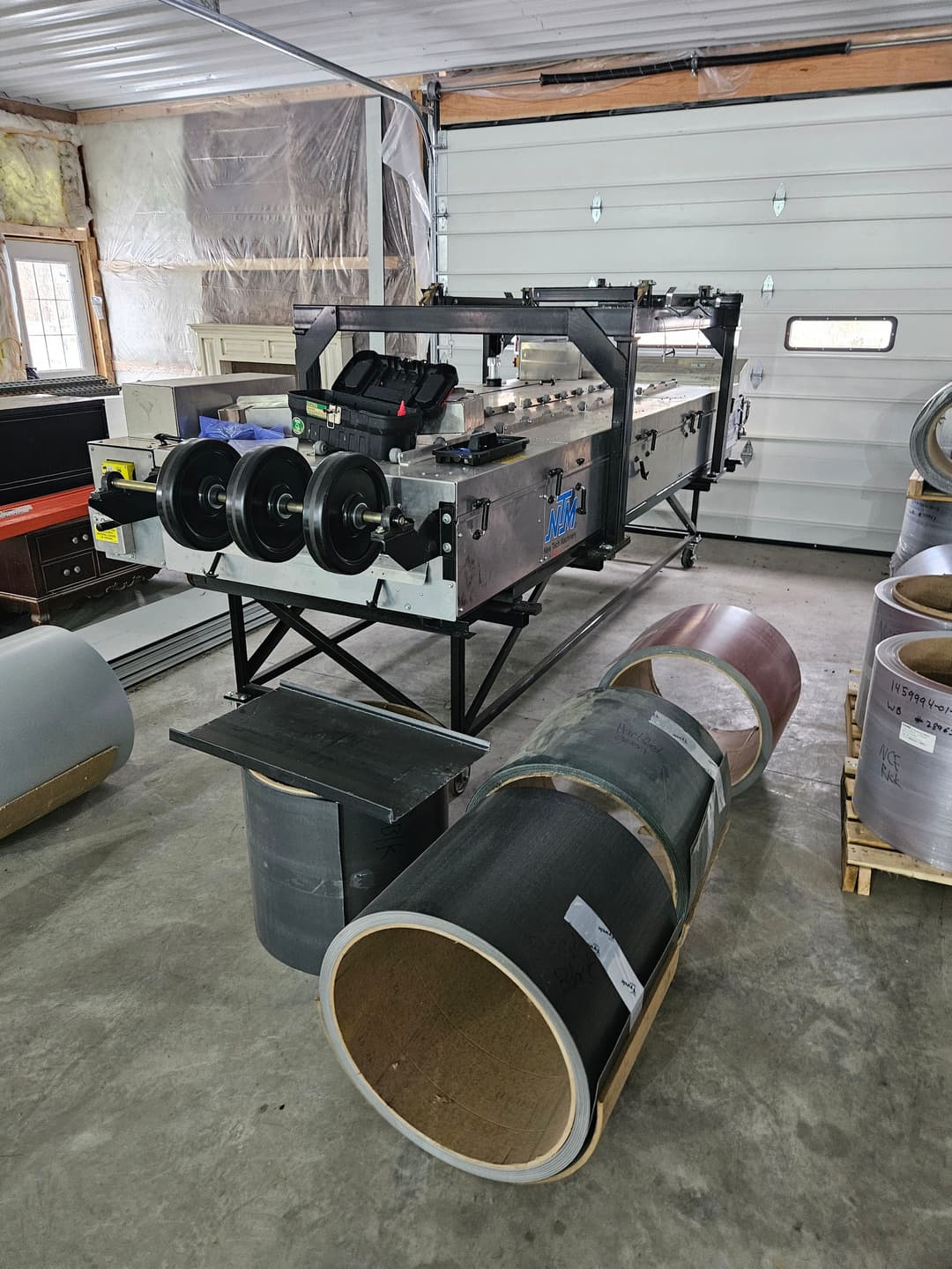 Industrial roll forming machine with metal coils and tools in a workshop setting.