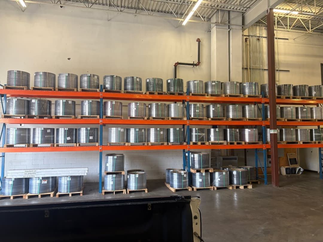 Storage warehouse with stacked metal barrels on shelves, showcasing organized inventory.